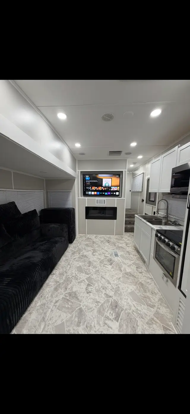 RV bedroom corner with open storage cubby holding a fan and adjacent white dresser drawers.