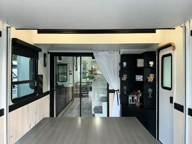 Toy hauler garage interior with corner shelving, side door, and sliding glass doors into main living area.
