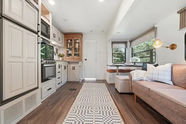Renovated RV main living area with sofa, kitchen, and dinette along one side.