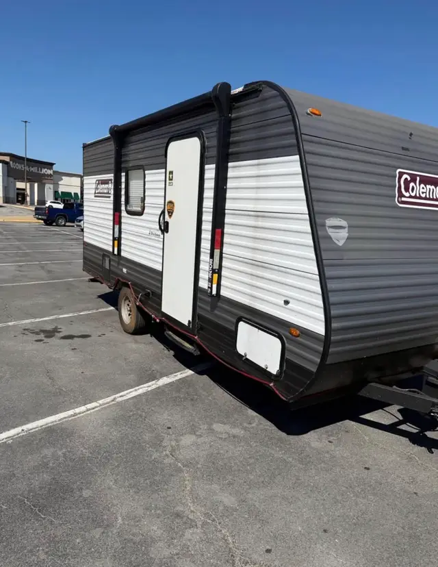 Front angle view of compact single-axle travel trailer with side door and awning hardware.