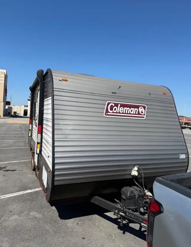 Close front view of travel trailer tongue with battery box and propane connection hitched to a pickup.