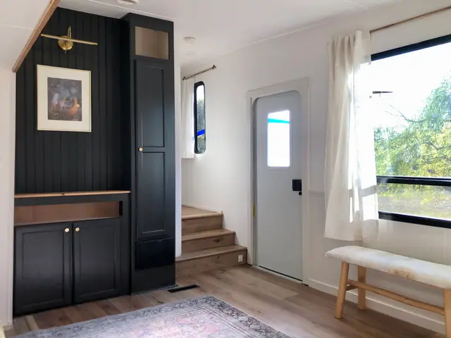 RV entry area with black feature wall cabinetry, bench seat, and steps to raised hallway.
