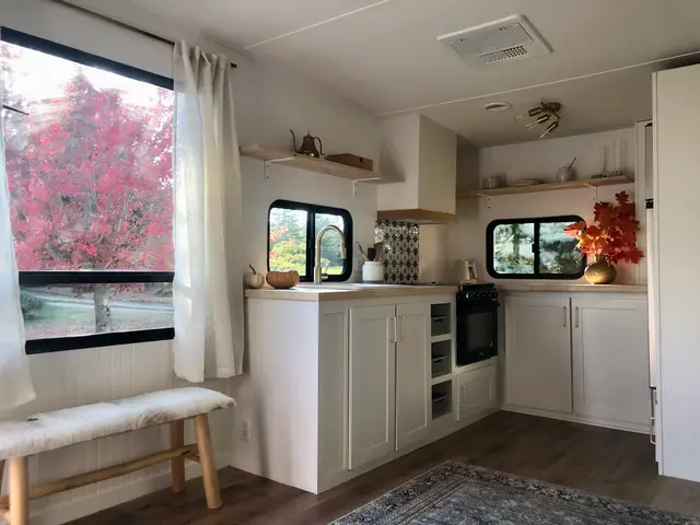 RV kitchen with large window, white cabinets, butcherblock counters, and decorative accents.