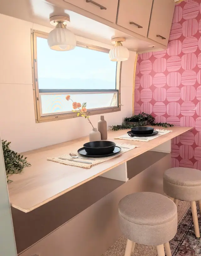 RV dining counter with stools, pendant lights, and window overlooking mountains.